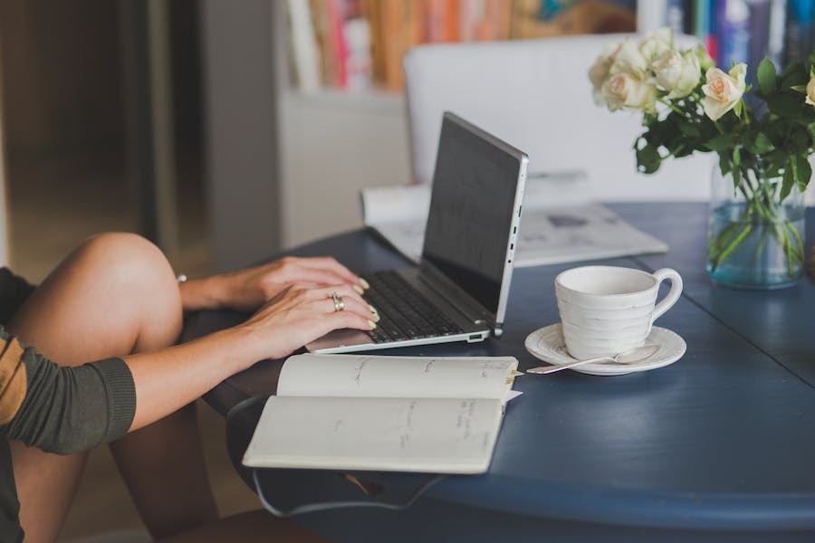 Woman sitting at the kitchen table with her laptop and a mug. 